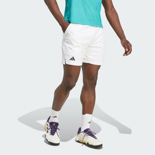 A person in a teal shirt, adidas Climacool Ergo Mens Tennis Shorts (white), white adidas socks, and white sneakers with purple and yellow accents stands against a plain light background.