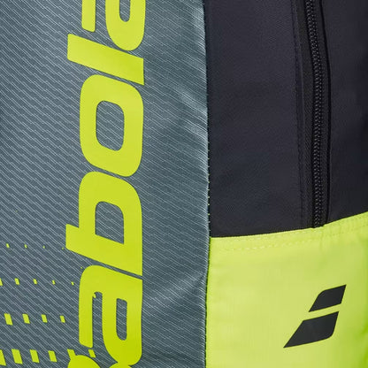 Close-up of the Babolat Kids Tennis Backpack - Metallic Grey / Fluo Yellow, showcasing a gray side panel with bold, bright yellow vertical "Babolat" text and a vibrant fluo yellow bottom section featuring a small black Babolat logo. These sections are divided by a black fabric strip with a zipper. Designed for young players, this Babolat kids tennis backpack combines style and functionality, making it an ideal tennis bag for children.