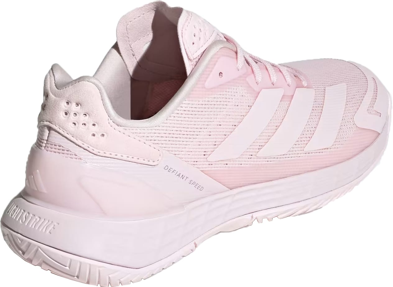 The adidas Defiant Speed 2 Womens Tennis Shoes in Distilled Pink feature a light pink mesh upper, iconic white adidas stripes, and a textured sole. Shown from a rear side angle, these athletic shoes provide a lightweight feel ideal for your next tennis match.