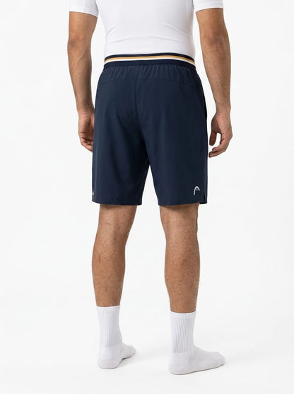 Back view of a person wearing HEAD Performance Mens Tennis Shorts - Navy, featuring a striped waistband and a small logo on the left leg.