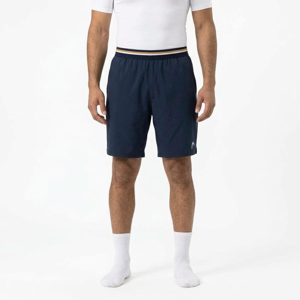 HEAD Performance Mens Tennis Shorts in navy with a 4-way stretch fabric and striped waistband, worn with a white t-shirt and white socks.