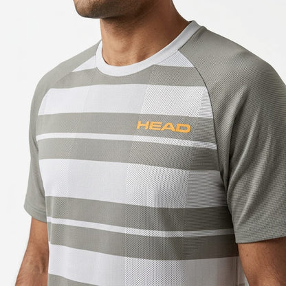 A person is wearing the HEAD Performance Mens Tennis T-Shirt - XPWG, a gray and white striped short sleeve athletic shirt from HEAD. Featuring bold orange “HEAD” lettering across the chest, this moisture-wicking tennis shirt is designed to deliver comfort and style for men both on and off the court. The individual’s face is not visible.