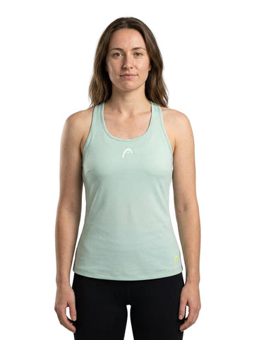 A woman with long brown hair wears a HEAD Spirit Womens Tennis Tank Top in Infinity Blue—crafted from advanced Moisture Transfer Microfibre sportswear fabric—and black pants, standing facing forward against a plain white background.