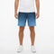 A man stands against a plain white background with his arms relaxed at his sides, wearing a white t-shirt, white sneakers, and HEAD Vision Power II Mens Tennis Shorts in Navy/Blue by HEAD, which feature 4-way stretch and moisture transfer microfiber.