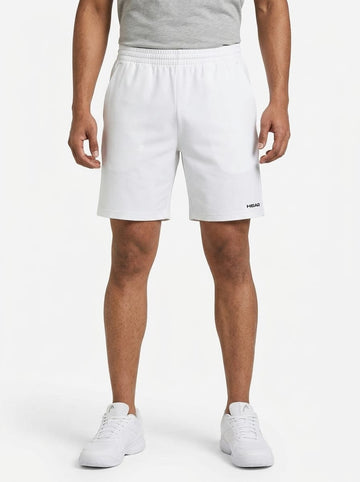 A person wearing a gray shirt and HEAD Vision Power Men’s Tennis Shorts in white—by HEAD, featuring 4-way stretch Moisture Transfer Microfiber for enhanced comfort and mobility—pairs the outfit with white sneakers while standing against a plain white background.