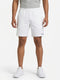 A person wearing a gray shirt and HEAD Vision Power Men’s Tennis Shorts in white—by HEAD, featuring 4-way stretch Moisture Transfer Microfiber for enhanced comfort and mobility—pairs the outfit with white sneakers while standing against a plain white background.