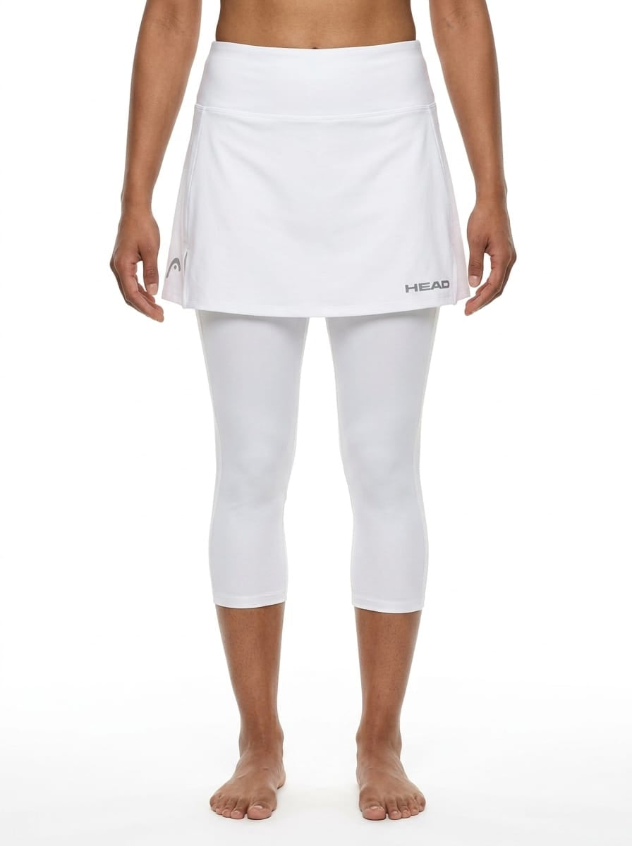 A person stands barefoot against a plain white background, wearing the HEAD Womens Club 3/4 Tights Tennis Skort in white by HEAD—an athletic skirt layered over matching capri-length tights made from moisture-wicking microfibre.