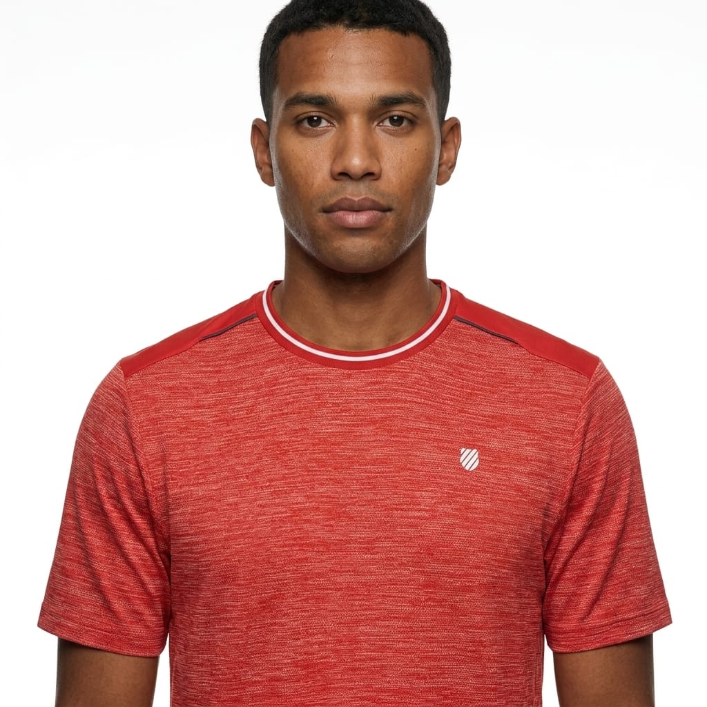 A man stands against a plain white background, looking directly at the camera with a neutral expression, wearing the K-Swiss Tac Hypercourt Tennis T-Shirt in Lollipop Melange—a comfortable, short-sleeve sportswear top featuring a small white K-Swiss logo.