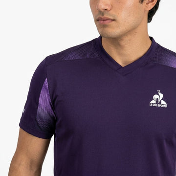 A man stands against a plain white background wearing the Le Coq Sportif Pro Men’s Tennis T-Shirt in Deep Purple, which features the iconic brand logo on the chest and is crafted from breathable sportswear fabric for comfort both on and off the court.