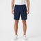 A person wearing a white t-shirt, Tecnifibre Team Stretch Men’s Tennis Shorts in Marine Blue, and white sneakers stands against a plain white background.