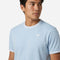 A person wearing a Tecnifibre Team Stretch Men’s Tennis T-Shirt in Glacier Blue looks to the side against a plain white background.