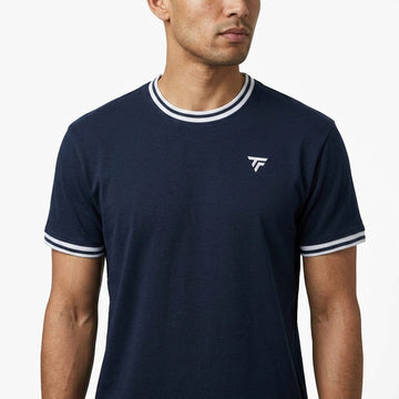 A man wearing the Tecnifibre Team Stretch Men’s Tennis T-Shirt in Marine Blue, a performance shirt featuring white trim on the collar and sleeves and a small white Tecnifibre logo on the left chest, stands against a plain white background.