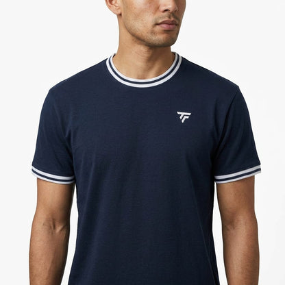 A man wearing the Tecnifibre Team Stretch Men’s Tennis T-Shirt in Marine Blue, a performance shirt featuring white trim on the collar and sleeves and a small white Tecnifibre logo on the left chest, stands against a plain white background.
