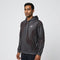 A man stands facing slightly left, wearing the Yonex YHD6 Unisex Tennis Hoodie - Storm in a black and gray pattern with a small white Yonex logo on the chest, against a plain light gray background.