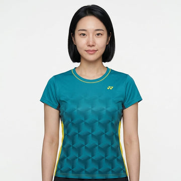 A woman with straight black hair wears the Yonex YTL12 Womens Tennis T-Shirt in teal—a stylish teal tennis shirt from Yonex featuring a geometric pattern and yellow accents—as she stands against a plain white background. Crafted from lightweight polyester, this top delivers comfort and style both on and off the court.
