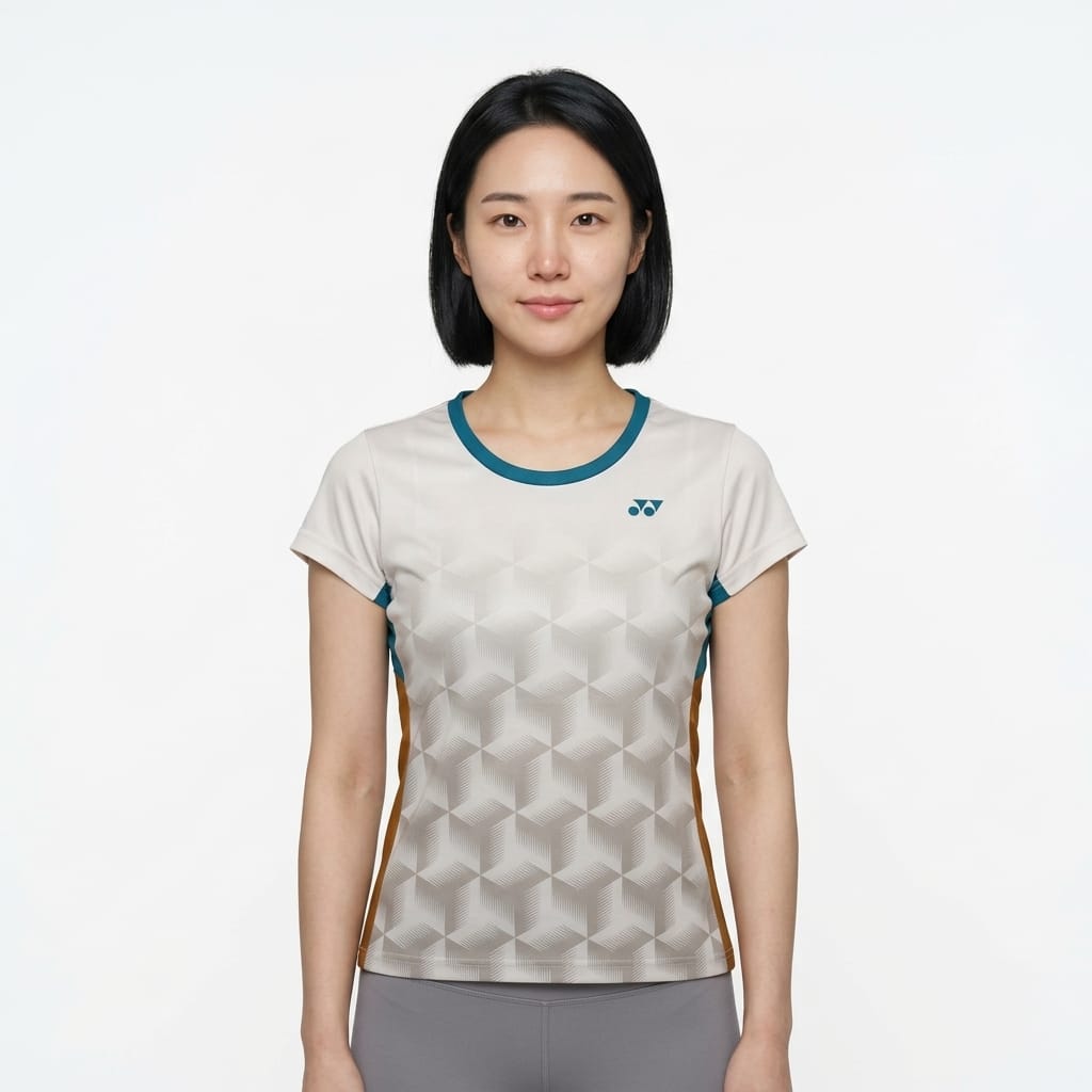 A woman with straight black hair, wearing a Yonex YTL12 Womens Tennis T-Shirt in white, stands facing the camera against a plain white background.