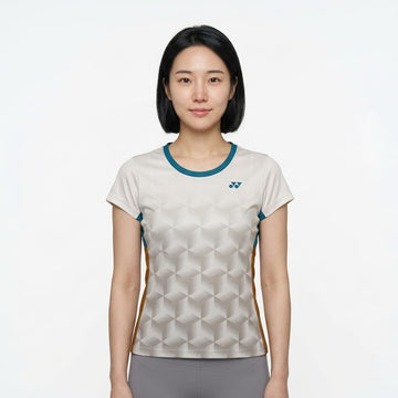 A woman with straight black hair, wearing a Yonex YTL12 Womens Tennis T-Shirt in white, stands facing the camera against a plain white background.