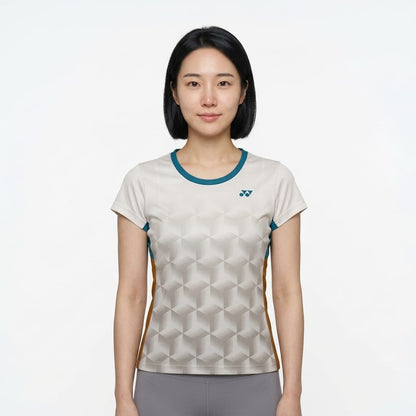 A woman with straight black hair, wearing a Yonex YTL12 Womens Tennis T-Shirt in white, stands facing the camera against a plain white background.