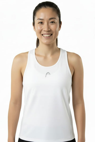Smiling woman with dark hair tied back poses against a plain white background, wearing the HEAD Club 25 Tech Women’s Tennis Tank Top in white—a sleeveless design featuring a small gray HEAD logo on the front and a sporty racerback for enhanced comfort.