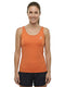 A woman stands smiling, wearing the HEAD Spirit II Womens Tennis Tank Top - CN by HEAD in orange—a sleeveless athletic top featuring cooling technology and a small white logo—paired with black shorts. She faces forward against a plain white background.