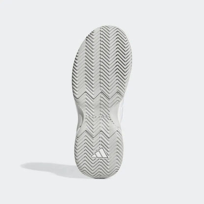 The image shows the sole of an adidas GameCourt 2 women's tennis shoe in white, featuring a herringbone tread pattern perfect for tennis play. It includes a subtle triangular adidas logo near the heel, with a shadow on the left suggesting it stands upright on a light surface, optimized for hard court outsoles.