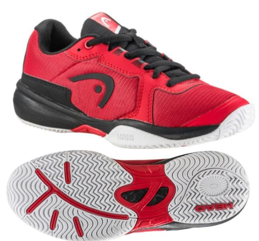 A pair of HEAD Sprint 3.5 Junior Tennis Shoes in red and black, displaying the brand's distinctive side logo. The image highlights a side view along with the sole, which has a textured white non-marking rubber design. These shoes feature black laces, breathable mesh construction, and a padded ankle collar for added support.