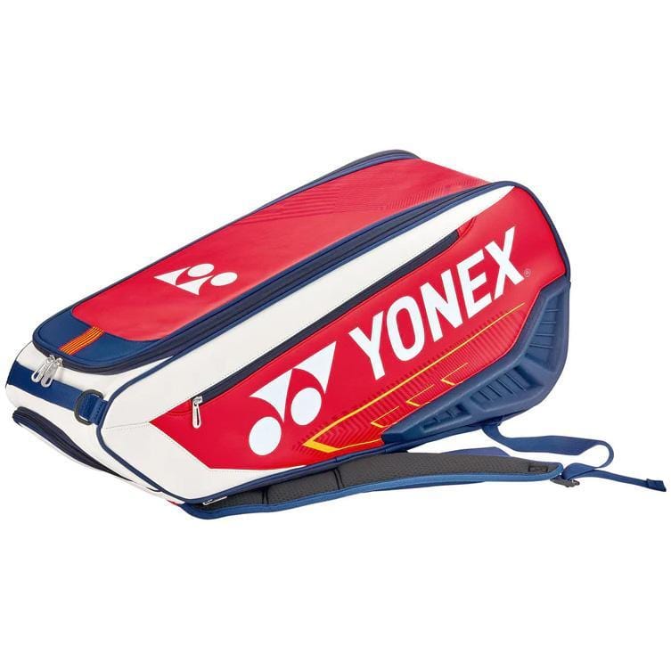 The Yonex 02326EX Expert 6 Piece Racket Bag combines white, navy, and red colors with eye-catching detailing and padded shoulder straps for comfort. Designed to carry tennis equipment, it boasts a sleek sporty design and includes a detachable laundry pouch for added convenience.