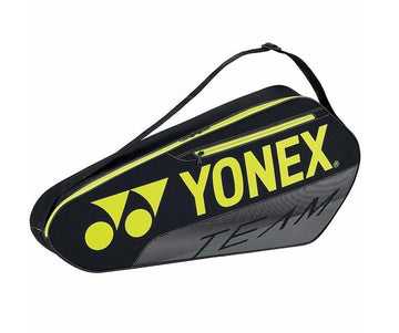 The Yonex Team 3 Racket Tennis Holdall, in black with yellow accents, features a shoulder strap and is perfect for organizing your racket. The Yonex brand name is prominently displayed in yellow letters alongside an abstract logo with the word "team" printed in lowercase near the bottom right corner.