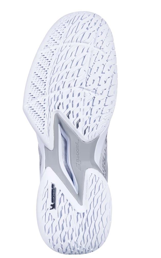 The image features the sole of a Babolat Jet Mach 3 All Court Men's Tennis Shoe in white and silver, showcasing a textured pattern for superior grip. Enhanced with Matryx Technology and multiple grooves, it includes gray accents in the middle area for extra support and shock absorption, optimizing performance.