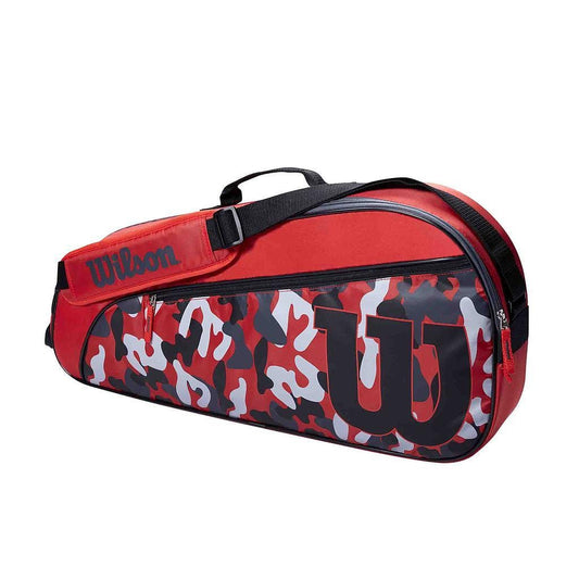 The Wilson Junior 3 Racket Tennis Bag - Red is a stylish tennis bag designed in red and black, featuring a bold camouflage pattern. It prominently showcases the Wilson brand logo and includes both a handle and shoulder strap, making it ideal for young athletes transporting their junior rackets to the court.