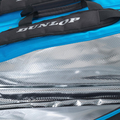 Close-up image of an open Dunlop FX Performance 12 Racket Thermo Tennis Bag - Black / Blue, showcasing its blue exterior and silver, reflective, insulated interior. The bag is partially unzipped to reveal the textured lining and specialized racket compartments that maintain a stable temperature for its contents.