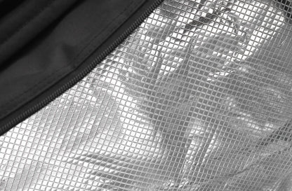 Close-up of a silver, reflective, metallic fabric featuring a grid-like pattern. A black zipper runs along the edge, contrasting with the textured surface. The material appears to be part of an insulated Dunlop CX Performance 12 Racket Thermo Tennis Bag in Black and Red.