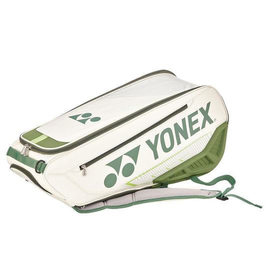 Introducing the Yonex 02326EX Expert 6 Piece Racket Bag in White/Moss Green, adorned with zippers and shoulder straps for easy carrying, and prominently displaying the Yonex logo on the side. For added convenience, it includes a detachable laundry pouch. The bag is showcased at a slight angle against a plain white background.