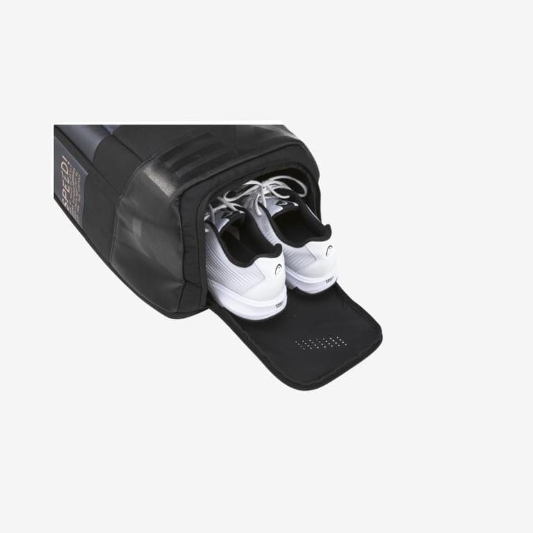 A pair of white athletic shoes with black accents peek out from the HEAD Djokovic Tennis Backpack in Black/Grey, which includes a ventilated shoe compartment, all set against a light gray background.