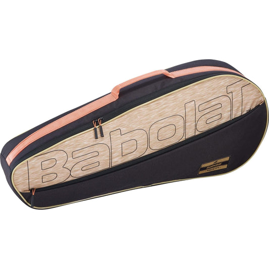The Babolat RH3 Essential 3 Racket Tennis Bag in black and beige prominently displays the Babolat brand name. This bag, designed to hold three rackets, includes a zippered pocket for additional storage and features an orange handle along with a tag that adds a retro logo charm.