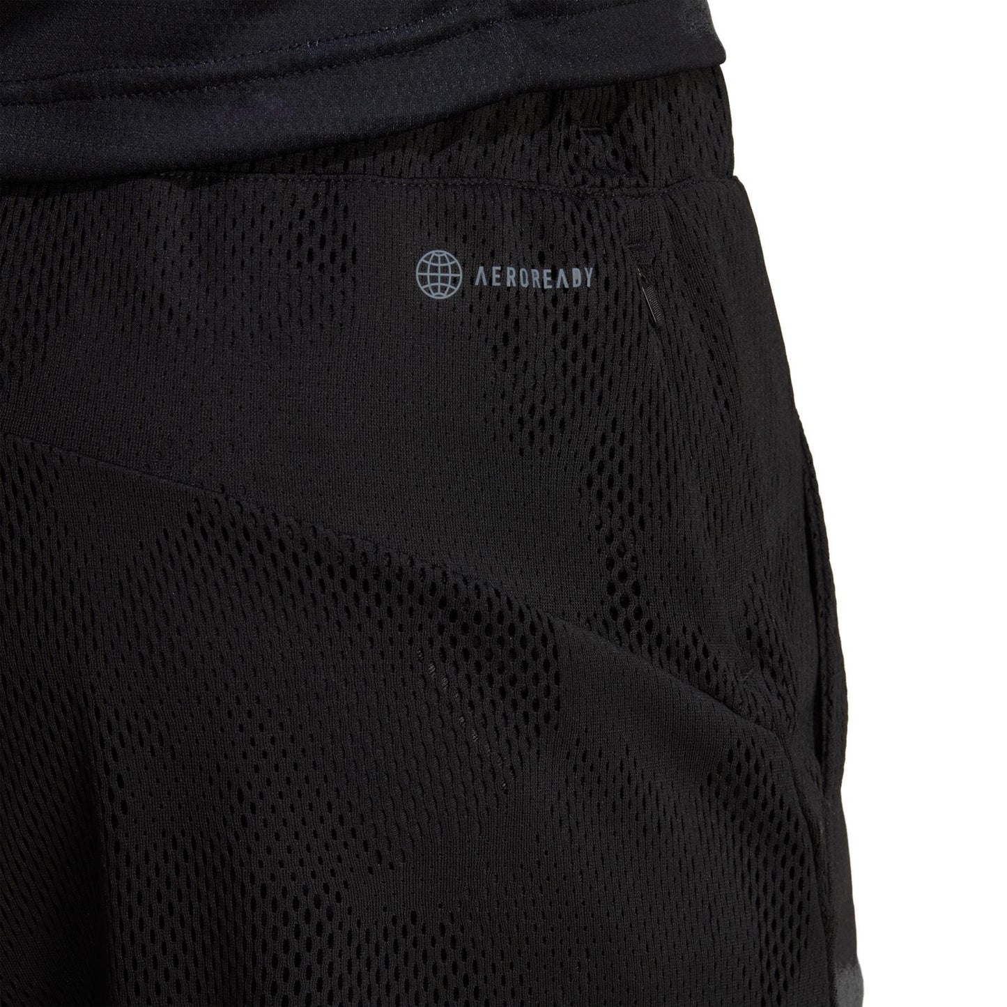 Close-up of the adidas Melbourne 2in1 Men's 7 Inch Tennis Shorts showcasing the "AEROREADY" logo. The black mesh fabric offers a textured, breathable design with an elastic waistband, making it perfect for athletic activities and incorporating sustainable carbon recycling materials.