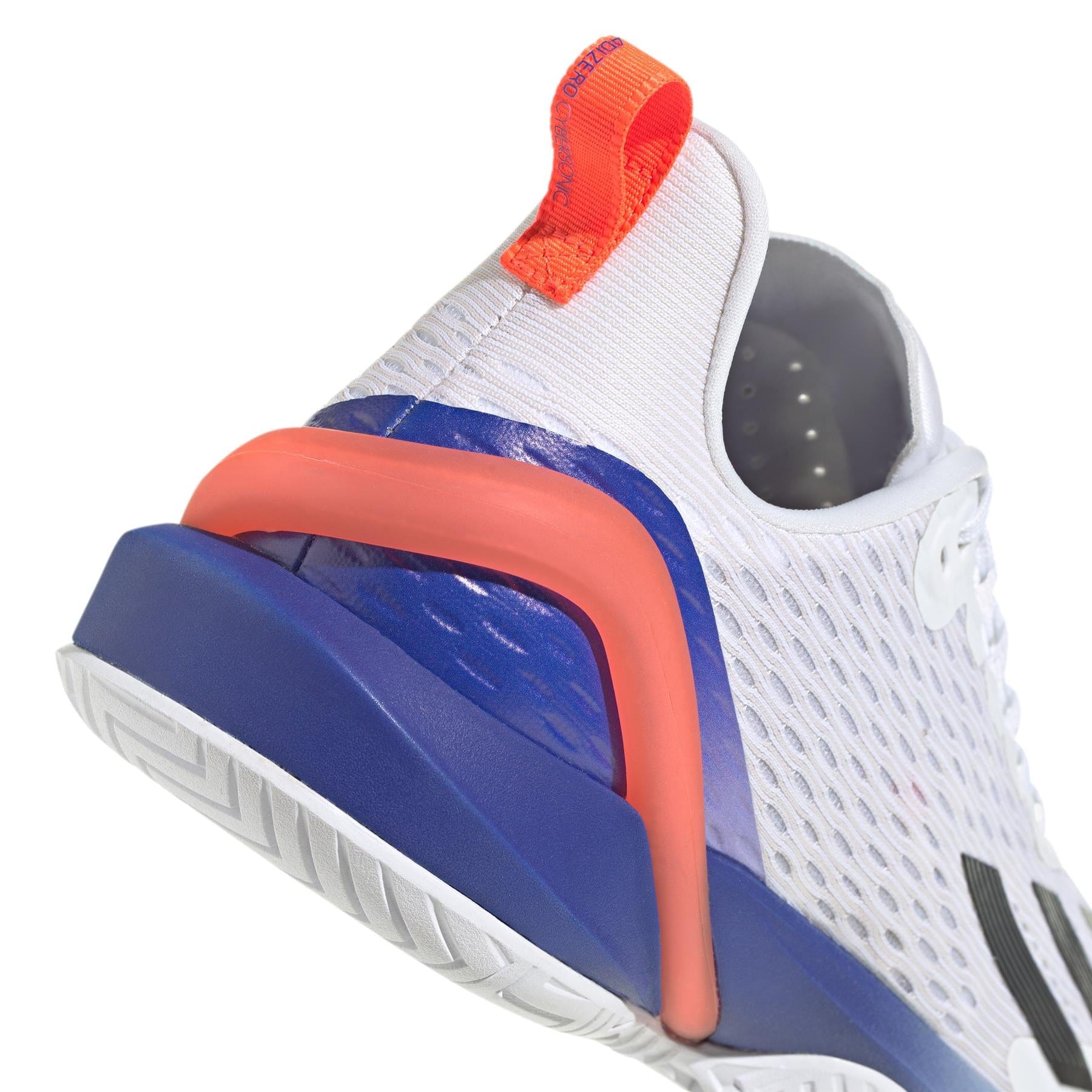 Close-up of a white athletic tennis shoe showcasing a textured mesh design, featuring a vibrant red sole and an orange pull tab at the heel. The adidas Adizero Cybersonic, available in Cloud White/Core Black/Solar Red, highlights a distinctive arch shape on its sole with geometric patterns, made from recycled materials for an eco-conscious performance.