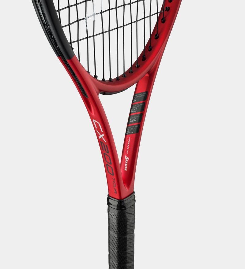 A close-up of a Dunlop CX200 Tour 16x19 310g tennis racket showcases its red frame with an open 16x19 string pattern complemented by black strings and grip. The "CX200" branding is clearly displayed on the side of its compact racket head amid other text details, set against a plain white background.