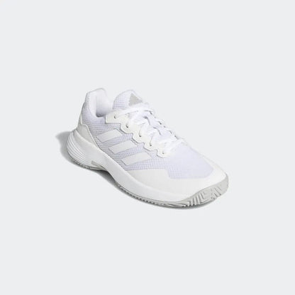 The adidas GameCourt 2 Women's Tennis Shoes in white are styled like traditional tennis footwear, showcasing a mesh upper, textured sole, and lace-up design. The recognizable GameCourt 2 logo by adidas is prominently displayed on the side of the shoe, and it is presented against a light gray backdrop in the photograph.