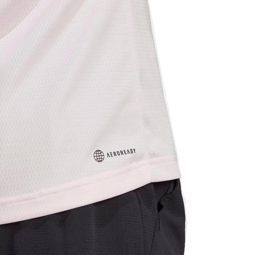 Close-up of a clear pink sports jersey featuring "AEROREADY" and a globe icon on the lower right side, hinting at its eco-friendly creation with recycled materials. The adidas Melbourne Men's Raglan Tennis T-Shirt is neatly tucked into black shorts, highlighting both style and sustainability.