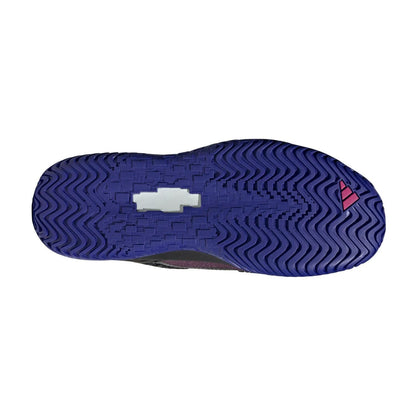 The image highlights the sole of the adidas SoleMatch Control Men's Tennis Shoes in black and blue, featuring a zigzag tread pattern in shades of blue and purple. Designed with Bounce Cushioning for comfort, it includes a small pink triangular logo near the heel and a white section at the center.