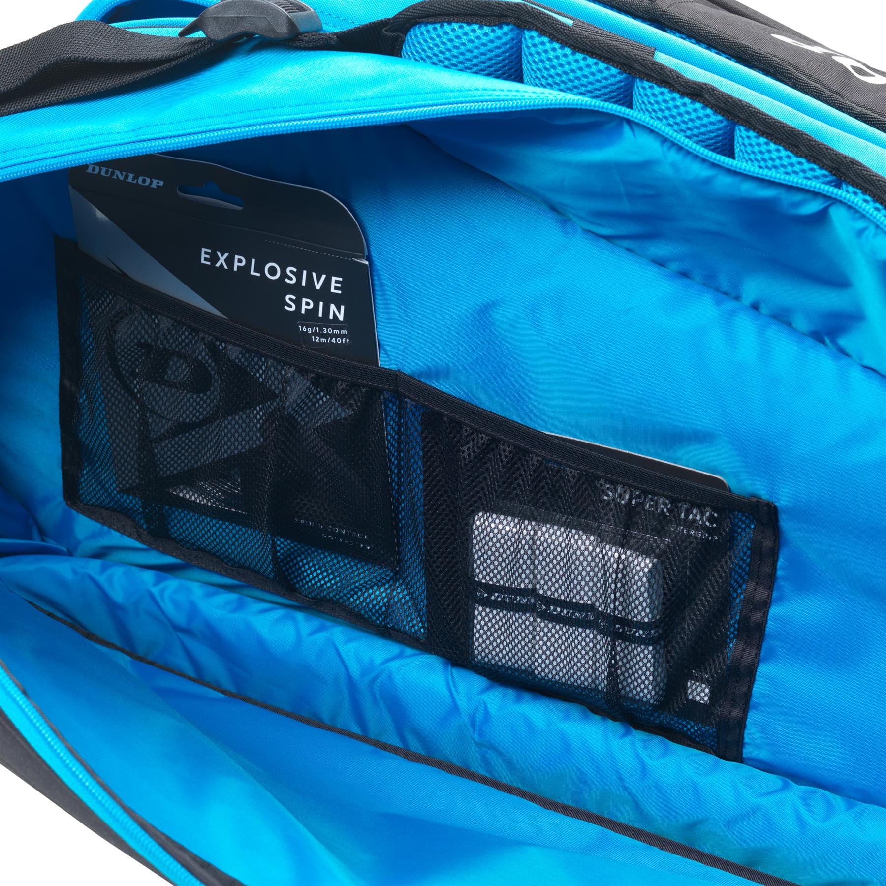 A close-up of the opened Dunlop FX Performance 12 Racket Thermo Tennis Bag, in black and blue, showcases its interior racket compartments. Inside, a mesh pocket contains packaged items, including one labeled "Explosive Spin" by Dunlop. The bag features black accents and a zippered section.